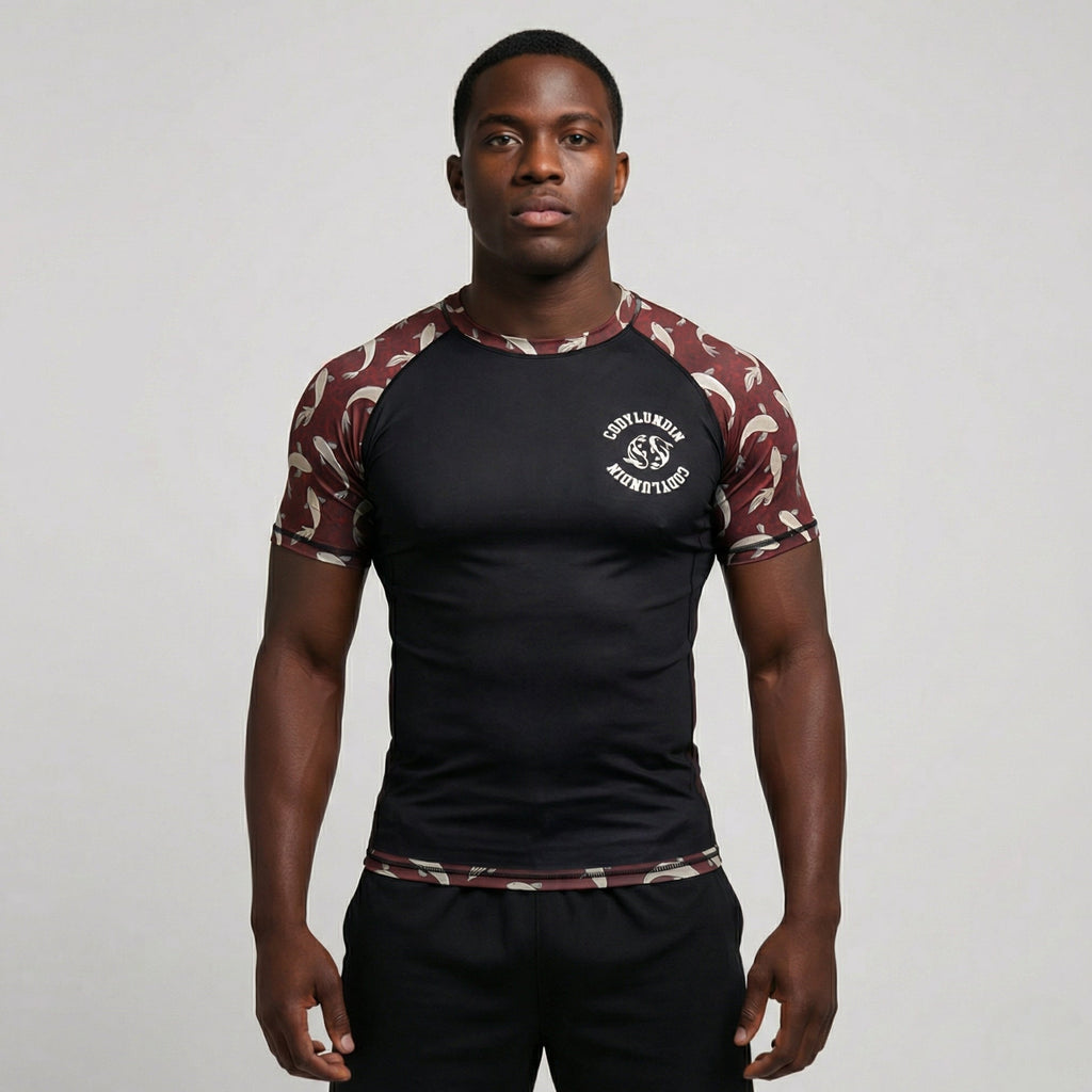 Man wearing a black athletic shirt with camouflage sleeves on a plain background