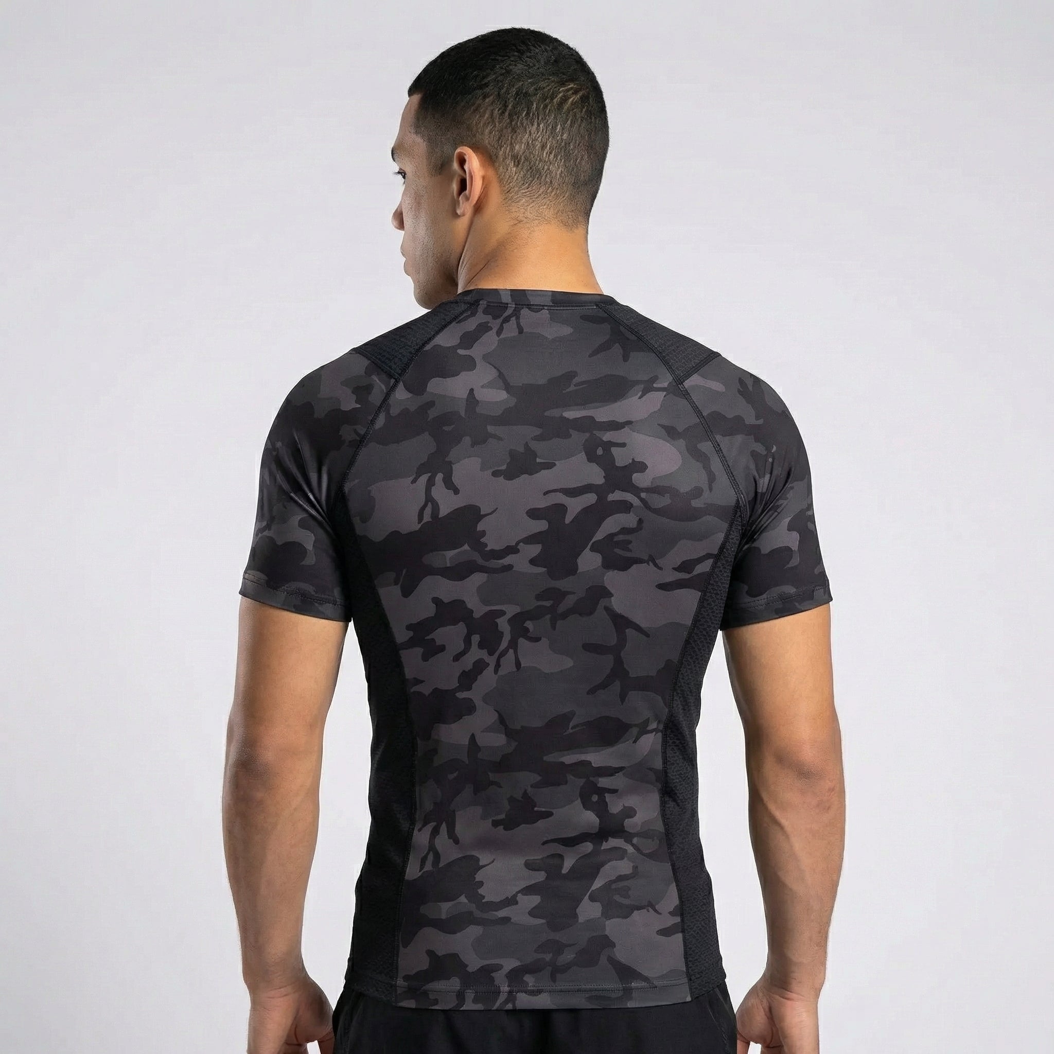 Person wearing a black camouflage athletic shirt on a white background