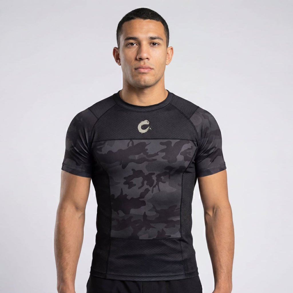 Man wearing a black athletic shirt with camouflage pattern on a white background