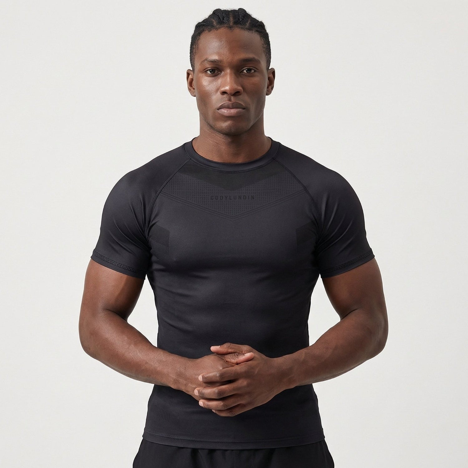 Man wearing a black athletic BJJ rash guard on a light gray background