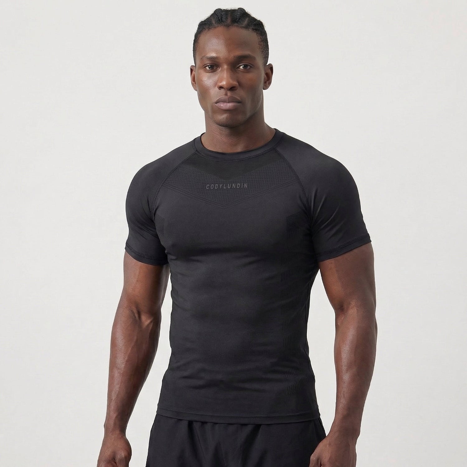 Man wearing a black athletic shirt with a visible brand logo on a light gray background